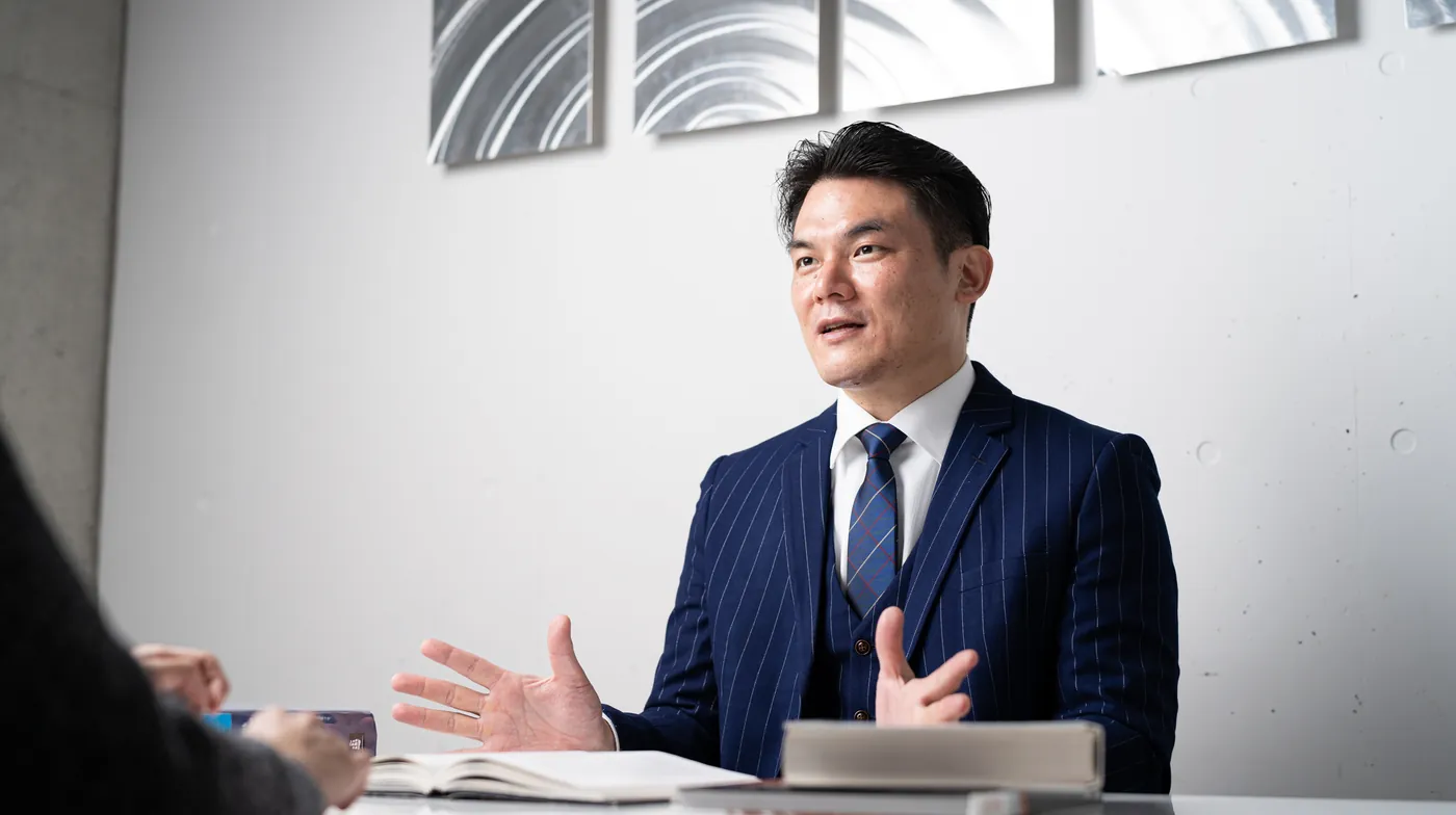 個別指導の様子。机の上の英語の本を前に、原 純一が受講生に説明している